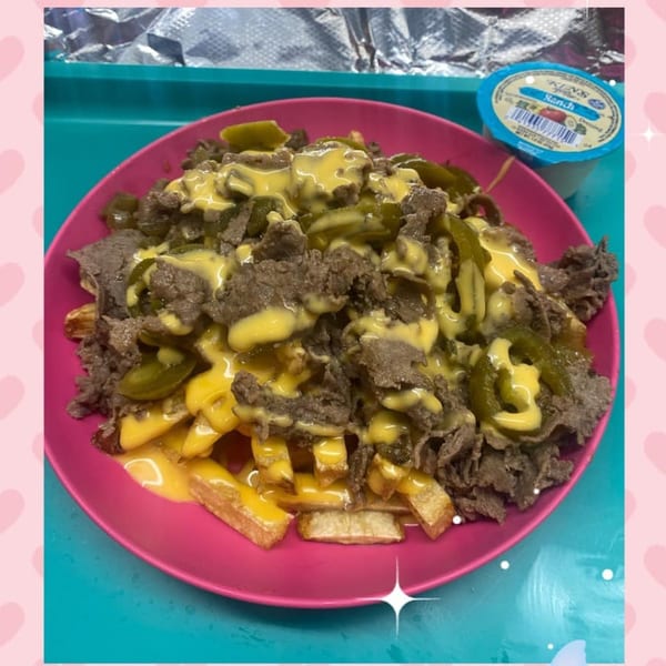 Philly Pete's cheesesteak fries, topped with melted cheese, steak, and jalapeños, with a side of ranch.